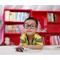 little boy with glasses laying on ground with open book
